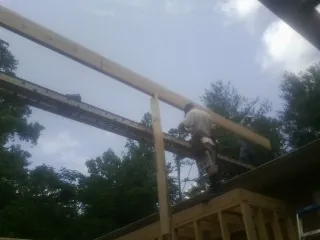 Carpenter setting a ridge beam over a new addition frame — Ice Dam Removal by Roofing Brothers in Neville
