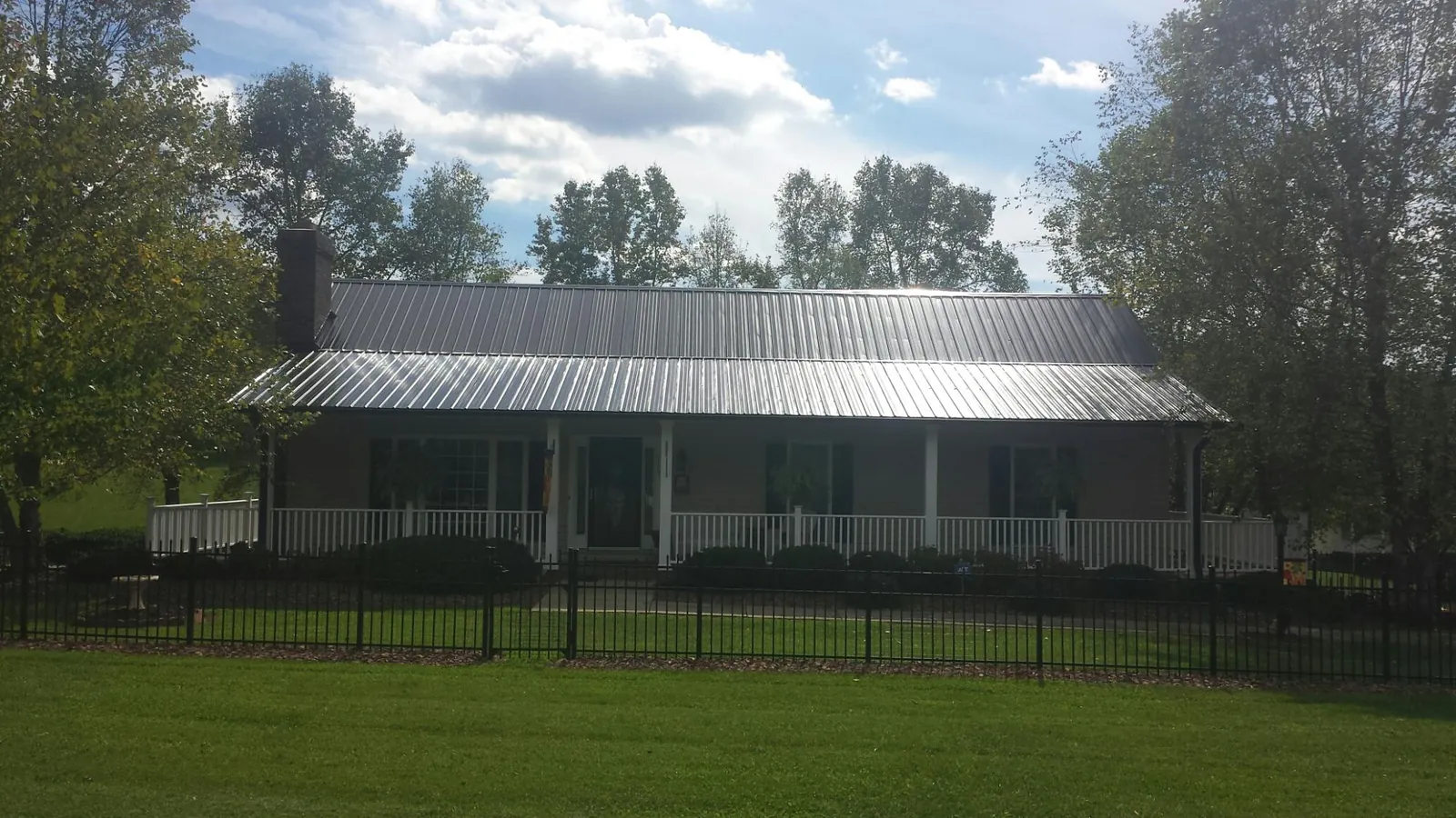 Gray metal roof on a brick ranch with a full width front porch — Gutter Guard Installation work by our crew in Neville