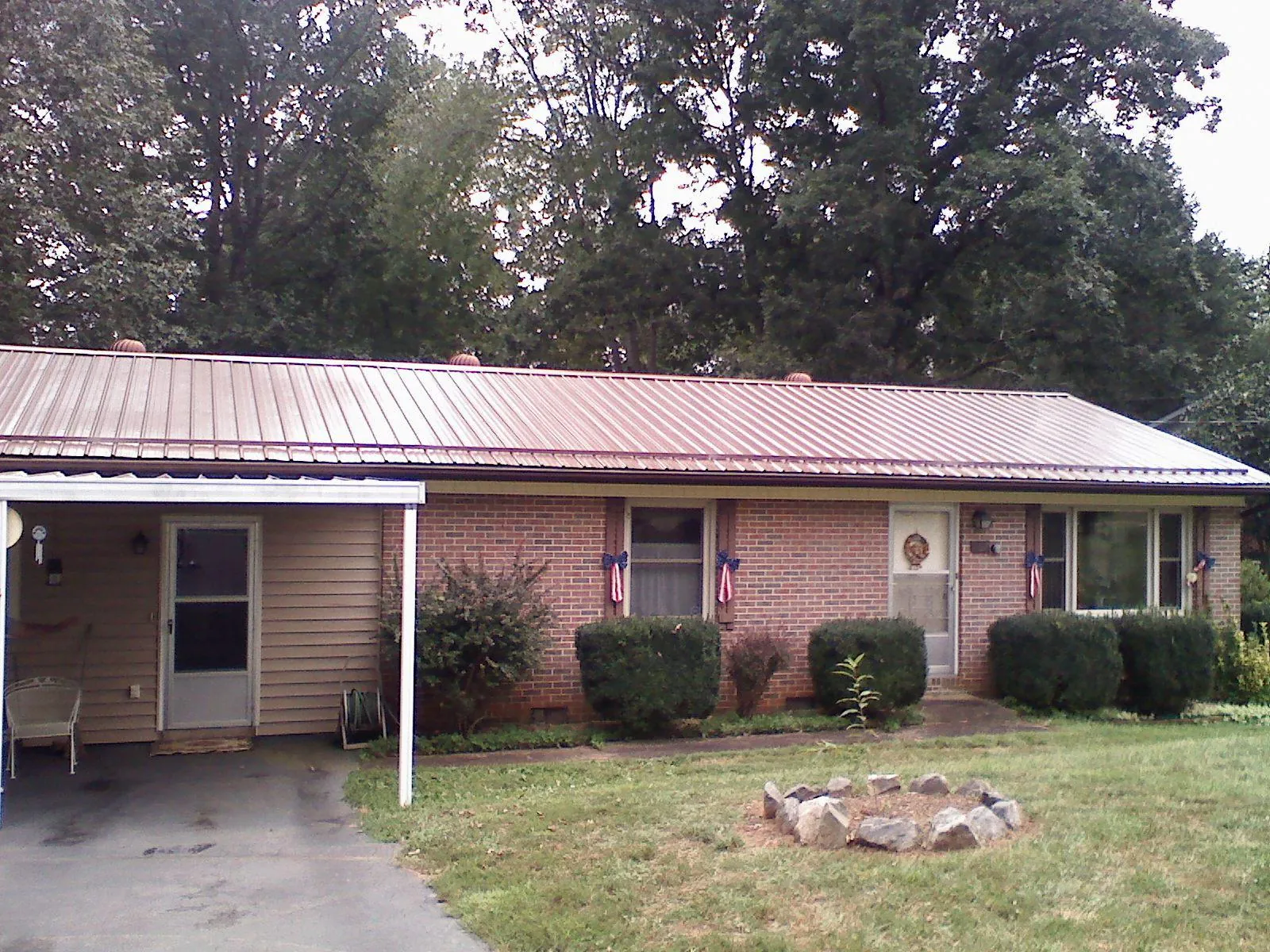 Bronze metal roof and carport on a brick ranch home — Roof Repair work by our crew in Neville