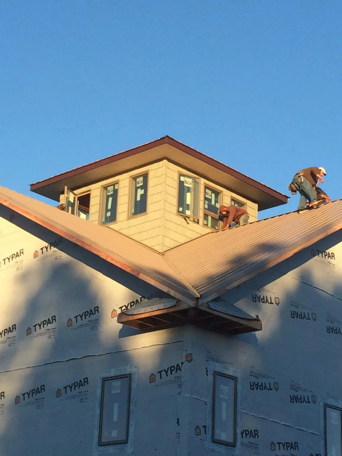 Roofers working around a rooftop cupola on a new metal roof at sunset — Roof Waterproofing in Neville by Roofing Brothers